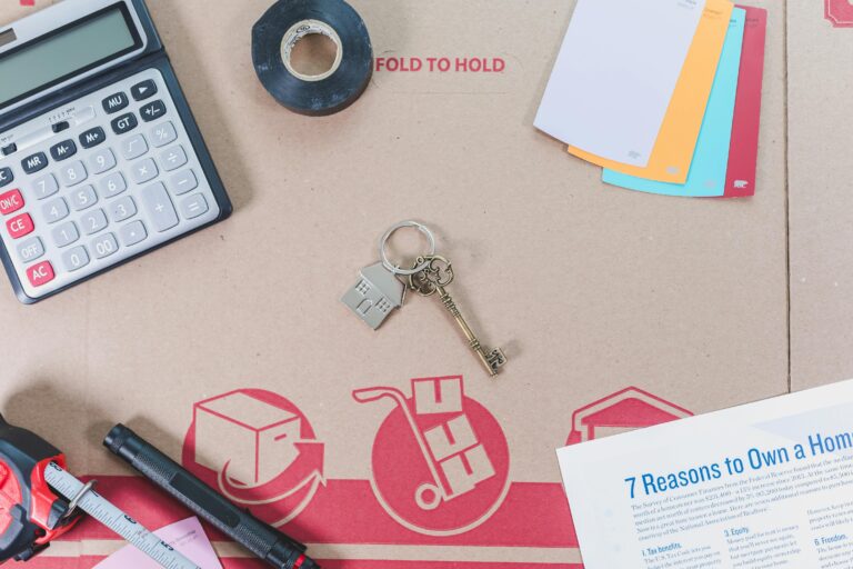 Flat lay of home buying essentials with calculator, keys, tape, and color swatches.